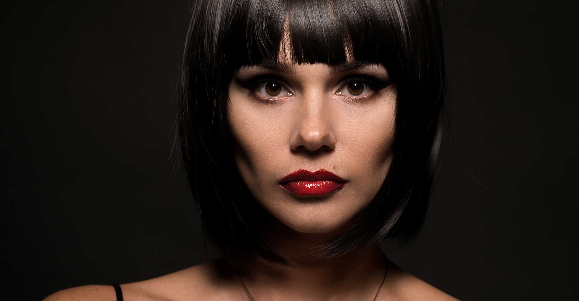 Mulher branca com batom vermelho e cabelo chanel preto com franja